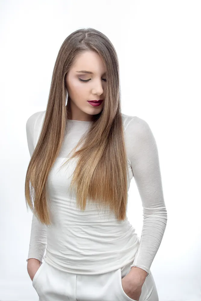 Donna in tuta bianca con le mani nelle tasche, gli occhi chiusi e il viso rivolto in basso