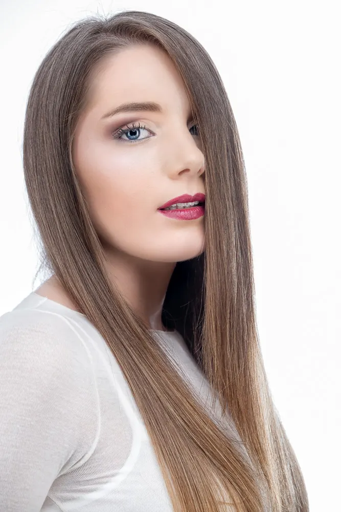 Ragazza ripresa di tre quarti, coi lunghi capelli lisci su un lato del viso e le labbra rosa scuro