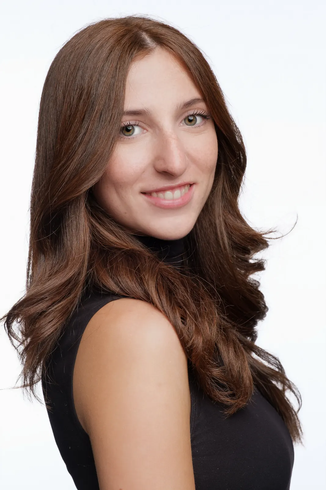Ragazza di tre quarti che sorride, coi capelli castani mossi e un top nero senza maniche