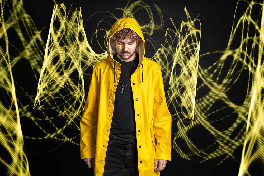 Musicista con l'impermeabile giallo fra le luci