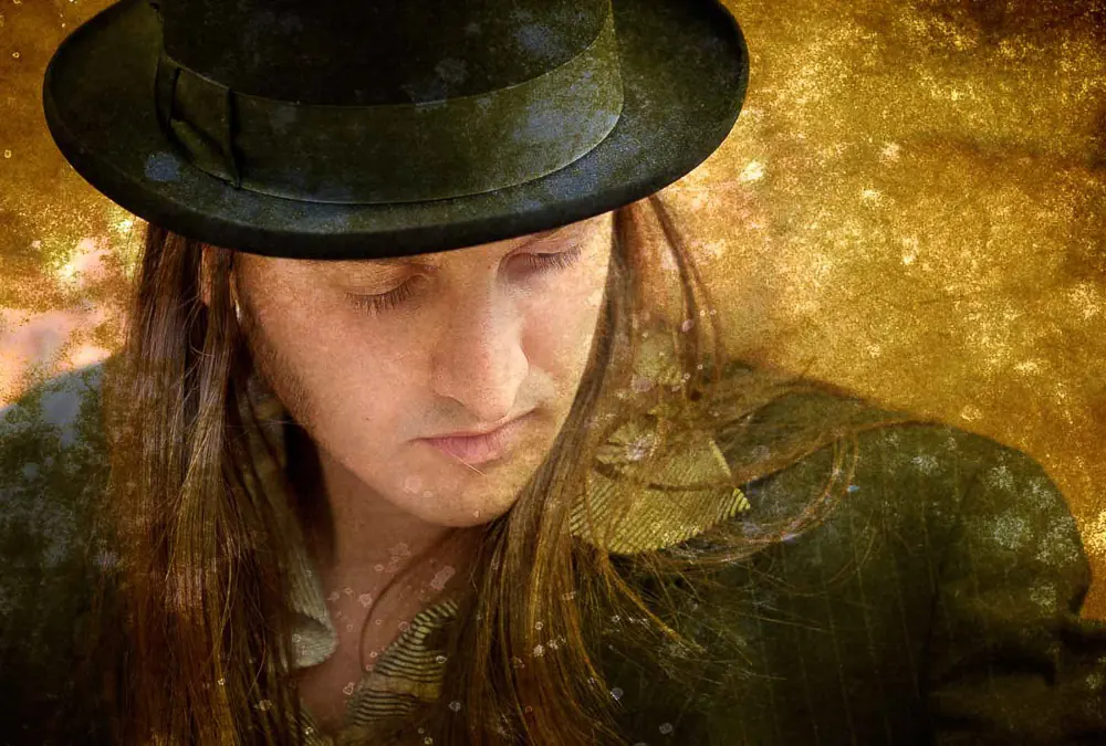 Musicista con cappello e capelli lunghi a occhi chiusi, su fondo dorato e consumato