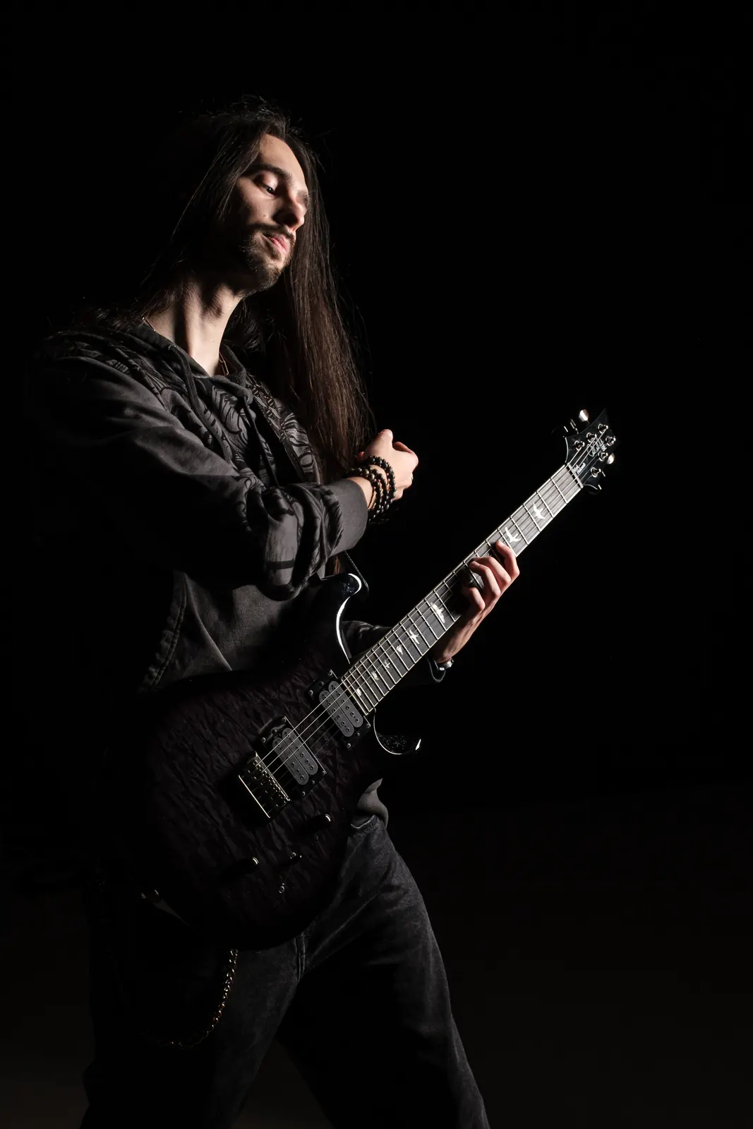 Chitarrista coi capelli lunghi e la testa inclinata, a occhi chiusi, mentre suona la chitarra nera